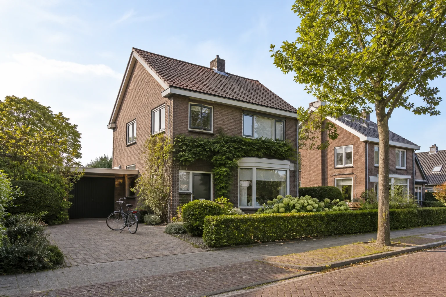 Representative brick family home with garden and driveway in Leende